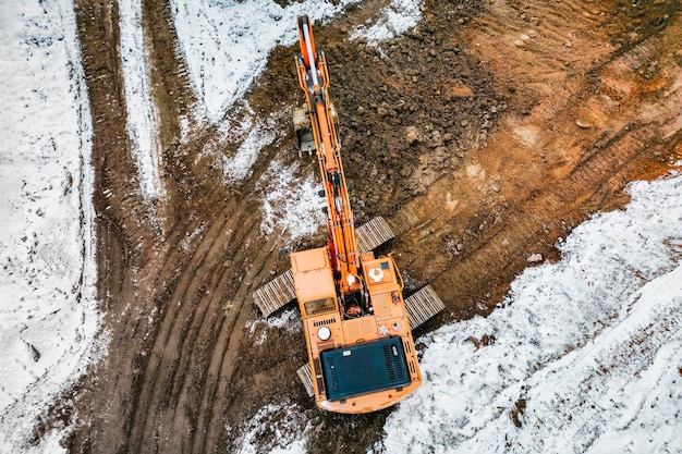 A powerful excavator digs the earth in northern conditions\
heavy construction machinery in winter conditions shooting from a\
drone closeup excavation with an excavator in the north