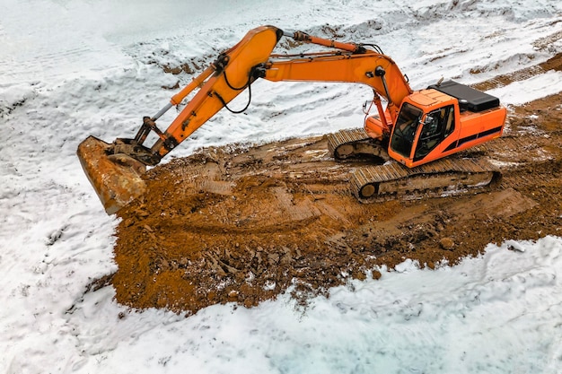 A powerful excavator digs the earth in northern conditions\
heavy construction machinery in winter conditions shooting from a\
drone closeup excavation with an excavator in the north