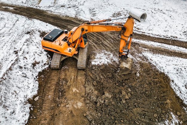 A powerful excavator digs the earth in northern conditions\
heavy construction machinery in winter conditions shooting from a\
drone closeup excavation with an excavator in the north