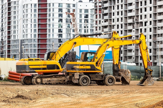 Powerful excavators at a construction site against a blue\
cloudy sky earthmoving construction equipment lots of\
excavators