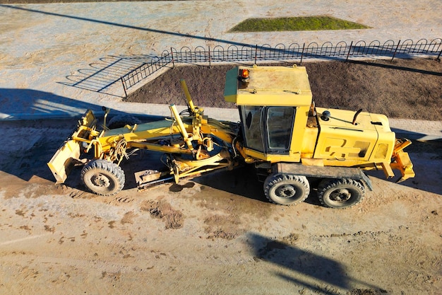 A powerful grader plans the surface of the earth while building\
a new road view from above drone photography earthworks with heavy\
equipment at the construction site