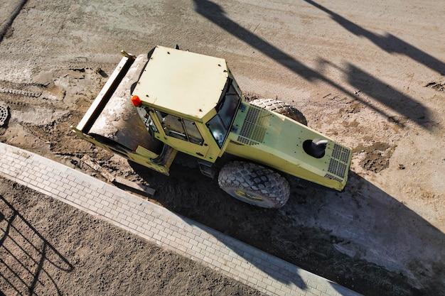 Powerful heavy road roller with a closed cabin view from above\
drone photography earthworks with heavy equipment at the\
construction site road construction equipment