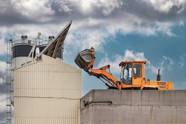 A powerful loader loads sand and crushed stone into a concrete plant. Industrial preparation of concrete. Heavy construction vehicle.