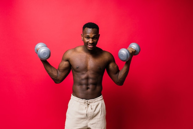 Powerful man doing the exercises with dumbbells on red background strength and motivation