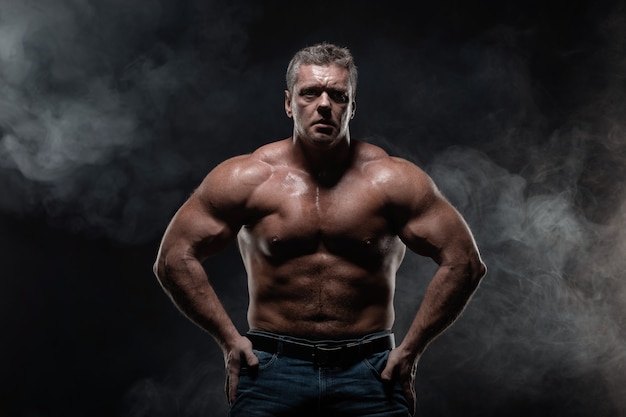 Powerful muscular bodybuilder posing on black. concept of strength and health