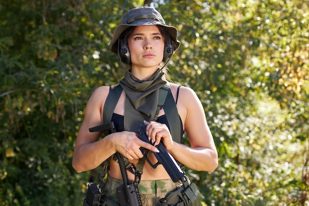 強力なスポーティーな女性兵士が保護用の軍事装備の武器を身に着けて戦闘の準備ができています