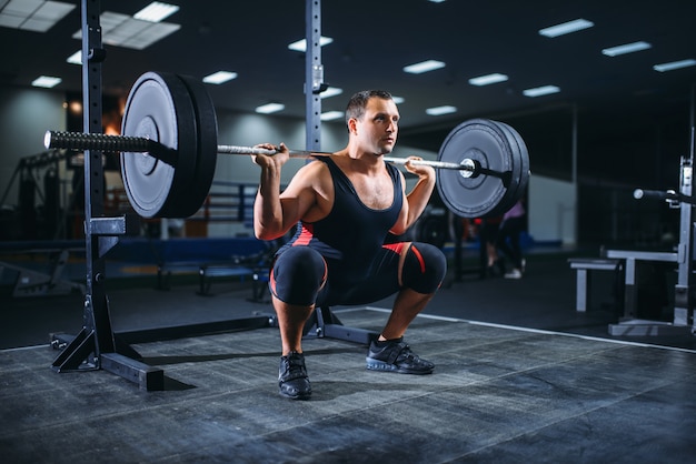 Powerlifter doet squats met barbell in sportschool