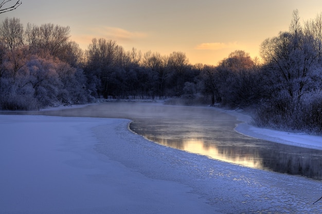 Prachtig betoverend uitzicht op de rivier die aan het begin van de lente smolt met bomen langs de kust op een koele lenteavond