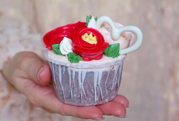 Prachtig bloemboeket frosting met hartvormige witte chocolade cupcake in de hand van de vrouw