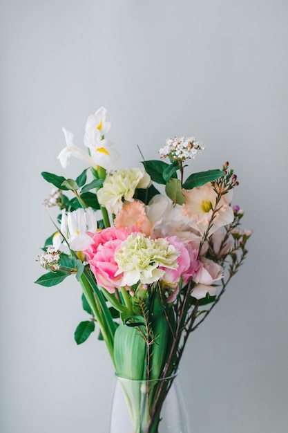 Prachtig boeket anjers narcissen trosrozen Chamelacium hookata en witte irissen op grijs