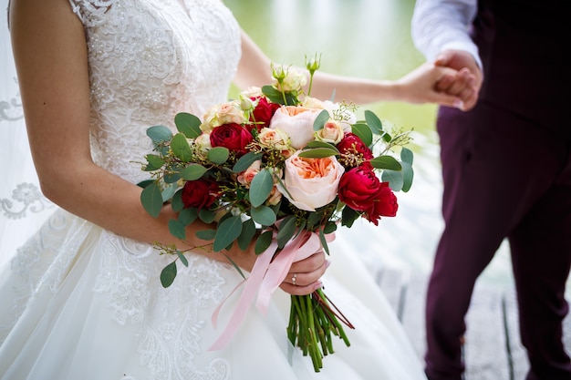 Prachtig bruidsboeket bloemen in de handen van de pasgetrouwden