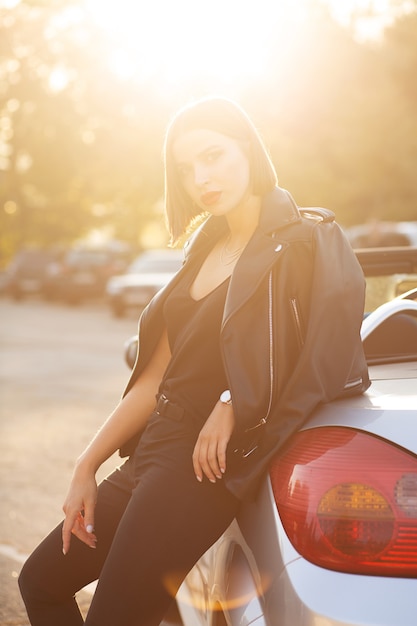 Prachtig brunette model met rode lippen poseren in de buurt van een cabriolet met schittering van de zon