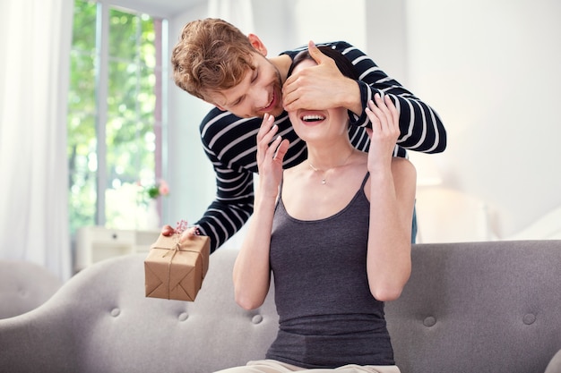 Prachtig cadeau. Gelukkig opgewonden vrouw die lacht in afwachting van een geschenk van haar vriendje