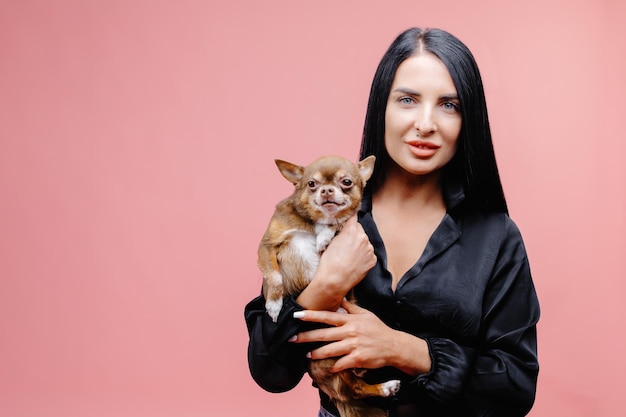 Prachtig Europees vrouwelijk model aan het chillen in de studio met puppy Binnenportret van een debonair meisje dat geniet van een fotoshoot met haar schattige huisdier