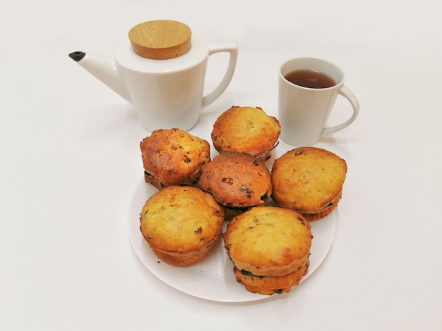 Prachtig geserveerde zelfgemaakte muffins met een witte theekop en theepot Thuis bakken