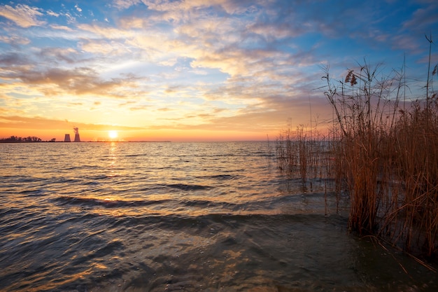 Prachtig landschap met avondrood, reservoir, riet en elektriciteitscentrale.