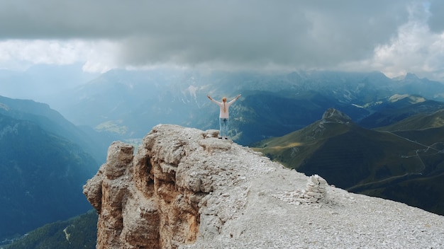 Prachtig landschap van bergrotsen en vrouw die met uitgestrekte armen op de top staat