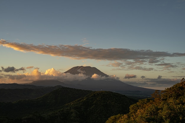 Prachtig landschap van bergvallei en majestueuze vulkaan omringd door dichte wolken stock foto