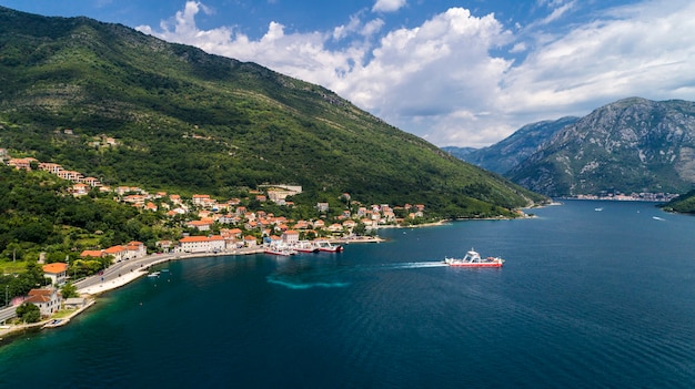 Prachtig luchtfoto van bovenaf naar de baai van Kotor en regelmatige passagiersveerboot van Lepetane naar Kamenari tegen een zonnige middag.