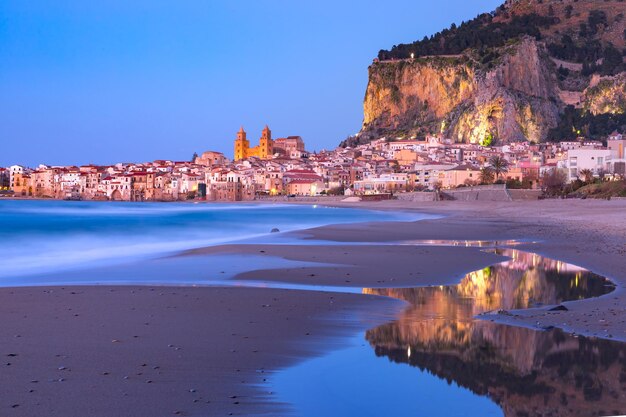 Prachtig panoramisch uitzicht op het strand en de oude stad van de kuststad Cefalu tijdens het blauwe avonduur, Sicilië, Italië