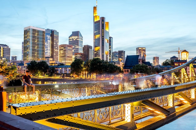 Prachtig stadsgezicht op de verlichte wolkenkrabbers en brug tijdens de schemering in Frankfurt, Duitsland