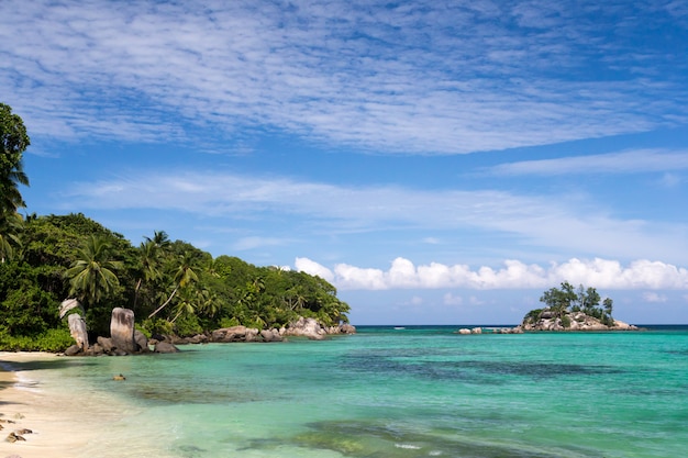 Prachtig strand met een klein eiland in de buurt van de Seychellen