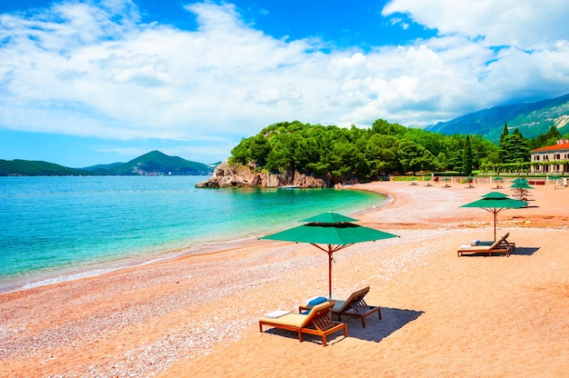 Prachtig strand met ligstoelen in de buurt van budva, montenegro. beroemde reisbestemming. zomerlandschap, uitzicht op zee en bergen