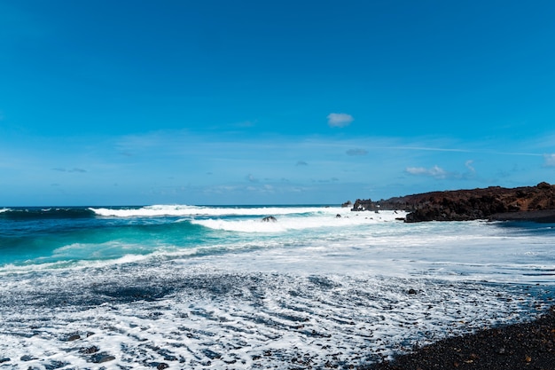 Prachtig strand op het eiland Lanzarote. Zandstrand omgeven door vulkanische bergen / Atlantische Oceaan en prachtig strand. Lanzarote. Canarische eilanden