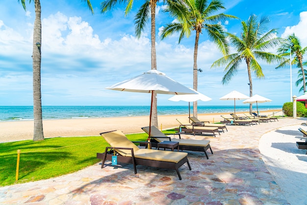 Prachtig tropisch strand en zee met parasol en stoel rond zwembad in hotelresort voor reizen en vakantie