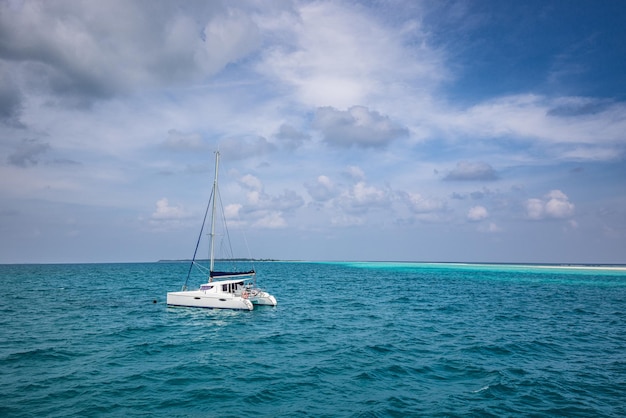 Prachtig turquoise water rond witte zeilboot verankerd in het midden van de oceaan. Bewolkte lucht oceaan lagune