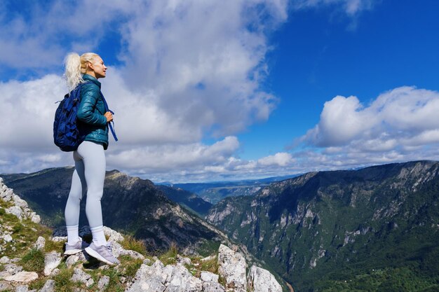 Prachtig uitzicht op de bergen Een jonge vrouw met een rugzak op de rand van een bergklif