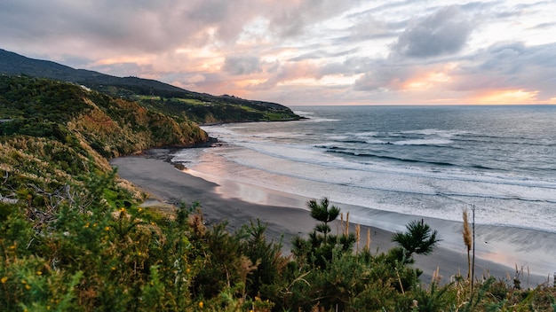 Prachtig uitzicht op de kliffen en het zeegebied tegen de schemering van de hemel op Ngarunui Beach Raglan Nieuw-Zeeland