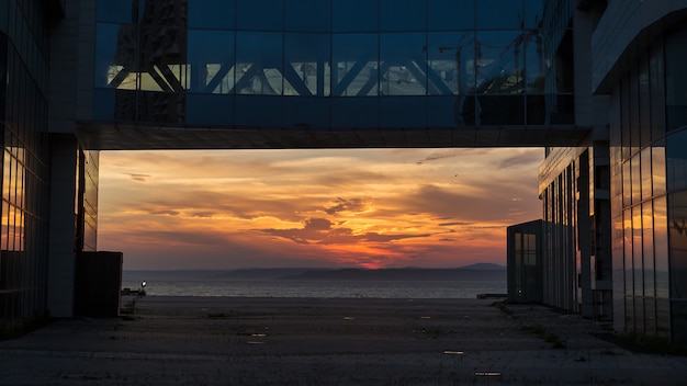 Prachtig uitzicht op de zonsondergang over de zee omlijst door glazen kantoorgebouw