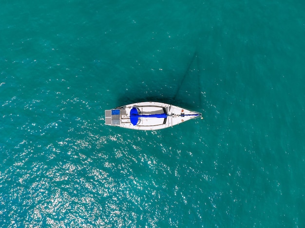 Prachtig uitzicht vanuit de lucht van een enorm wit en blauw jacht dat over de blauwe lagune vaart