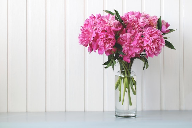 Prachtig weelderig boeket van roze pioenrozen in een glazen vaas