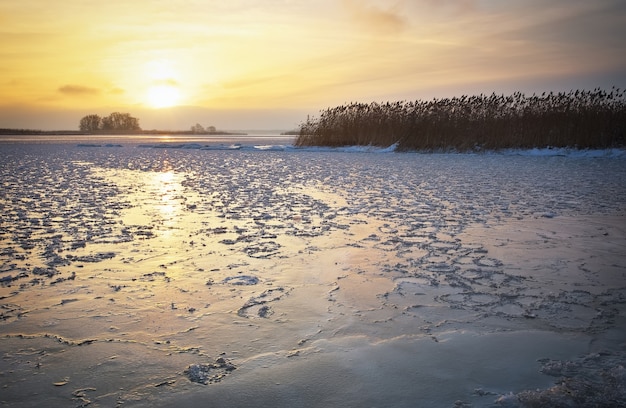 Prachtig winterlandschap met bevroren meer en avondrood. Samenstelling van de natuur.
