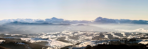 Prachtig winterpanorama met verse sneeuw. Landschap met vuren pijnbomen, blauwe lucht met zonlicht en hoge Karpaten op de achtergrond.