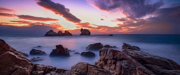 Prachtig zeegezicht bij zonsopgang met wolken in de lucht getextureerde stenen in de voorgrondfragmenten