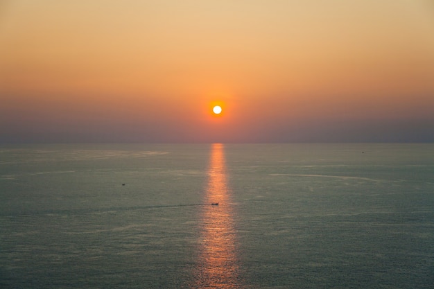 Prachtig zeegezicht met zonsondergang en een boot in de stralen