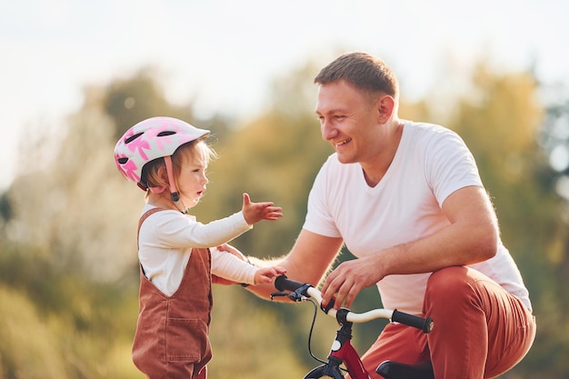 Prachtig zonlicht Vader in wit overhemd leert dochter hoe ze buiten moet fietsen