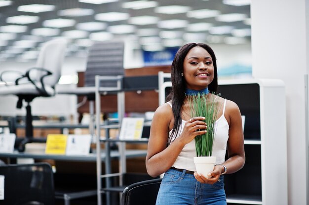 Foto prachtige afro-amerikaanse vrouw met mooie kleine plant in de winkel