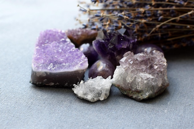 Prachtige amethist stenen en amethist druze met droog lavendelboeket op katoenen stof Magische amuletten