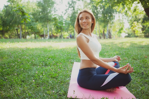 Prachtige atletische vrouw doet yoga in het park