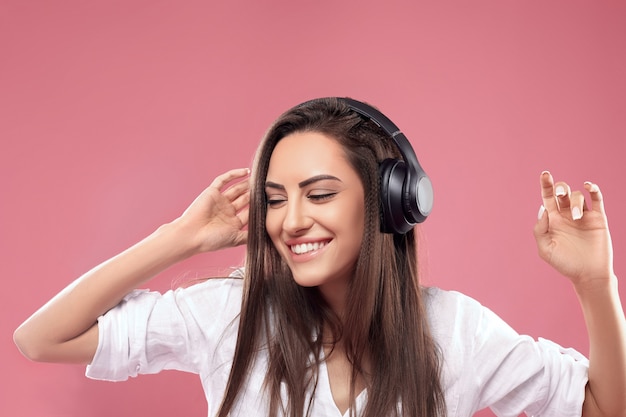 Prachtige brunette dame luisteren muziek in draadloze hoofdtelefoons en zingen