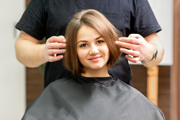 Prachtige brunette kort haar vrouw en haar mannelijke kapper kijken en controleren kapsel mooi kapsel van een jonge brunette vrouw resultaten van haarbehandeling in een schoonheidssalon