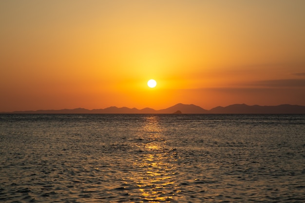 Prachtige gouden zonsondergang aan zee en de bergen