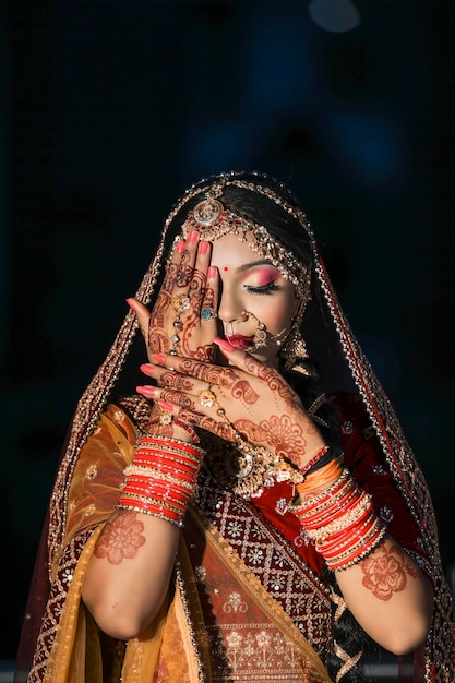 Prachtige Indiase bruid gekleed in traditionele trouwkleding lehenga geborduurd met gouden sieraden