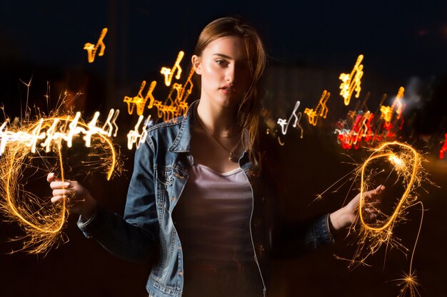 Prachtige jonge brunette vrouw poseren met Bengaalse lichten op de night avenue