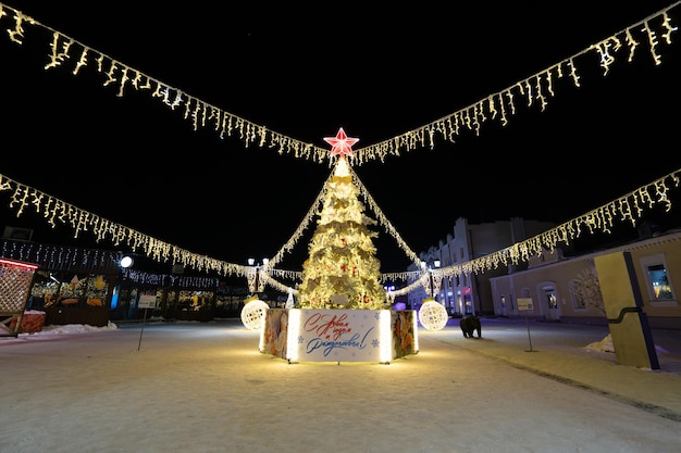 prachtige kerstboom met versieringen en verlichting in de sneeuwnacht Nieuwjaar en kerstvakantie achtergrond feestelijke winter stadslandschap