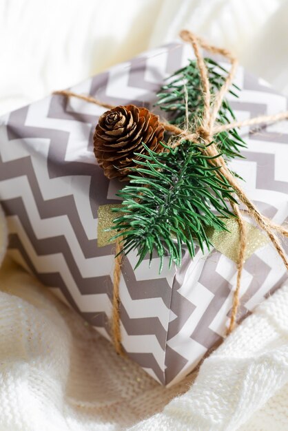 Prachtige kerstcadeaudoos gedecoreerd met groene natuurlijke dennentakje en dennenappel, verpakt in feestelijk papier